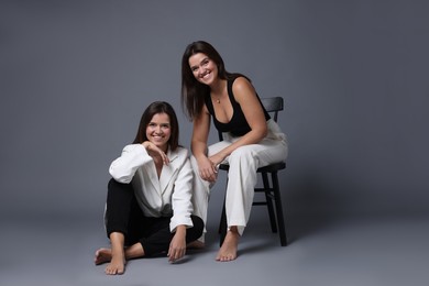 Portrait of beautiful twin sisters on grey background