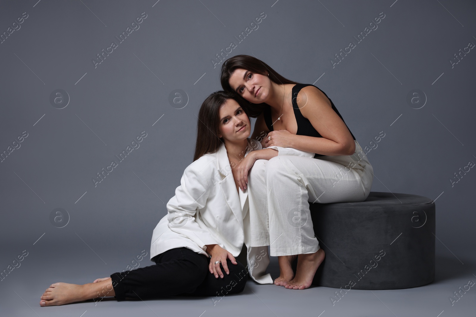 Photo of Portrait of beautiful twin sisters on grey background