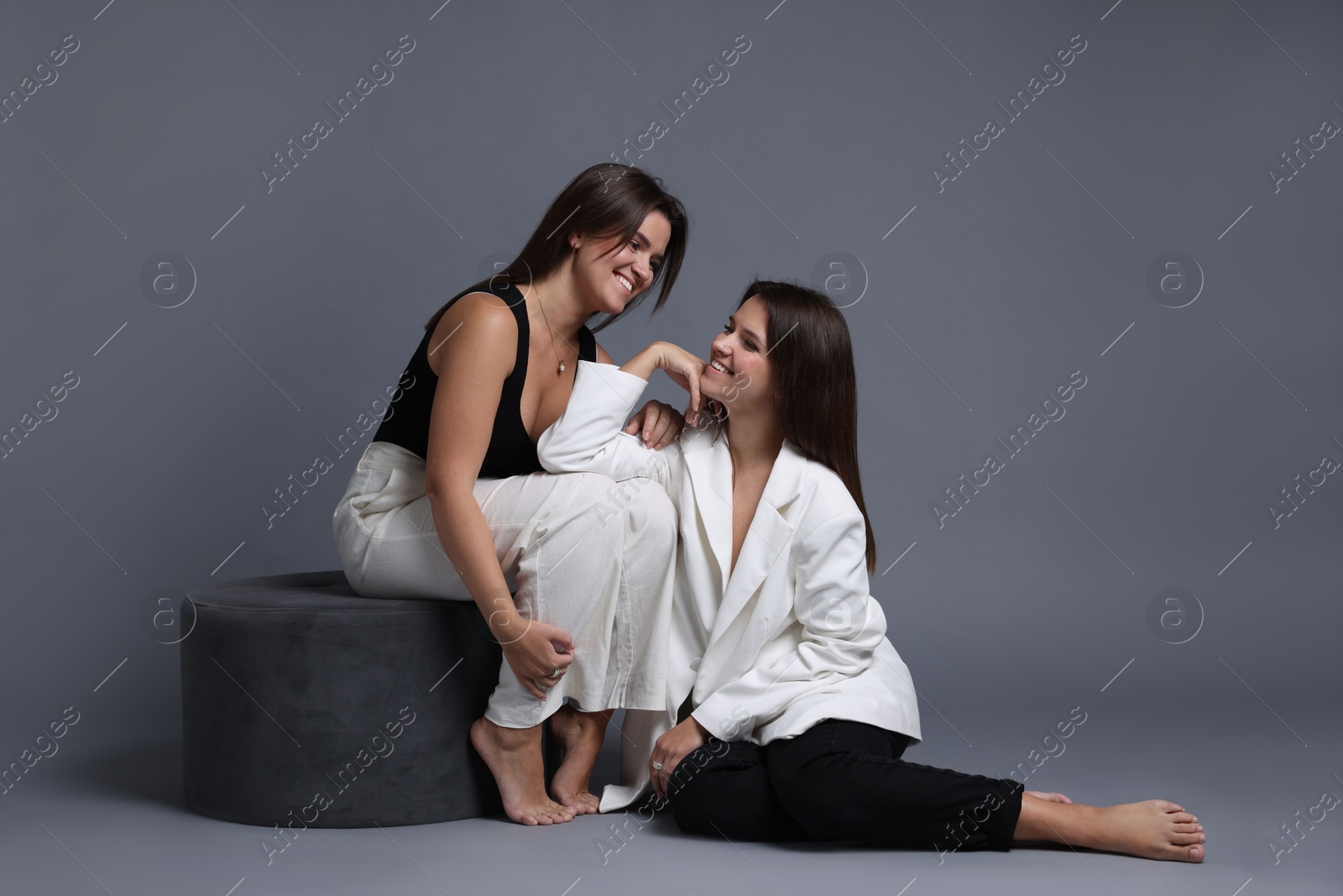 Photo of Portrait of beautiful twin sisters on grey background