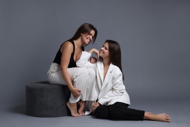 Portrait of beautiful twin sisters on grey background