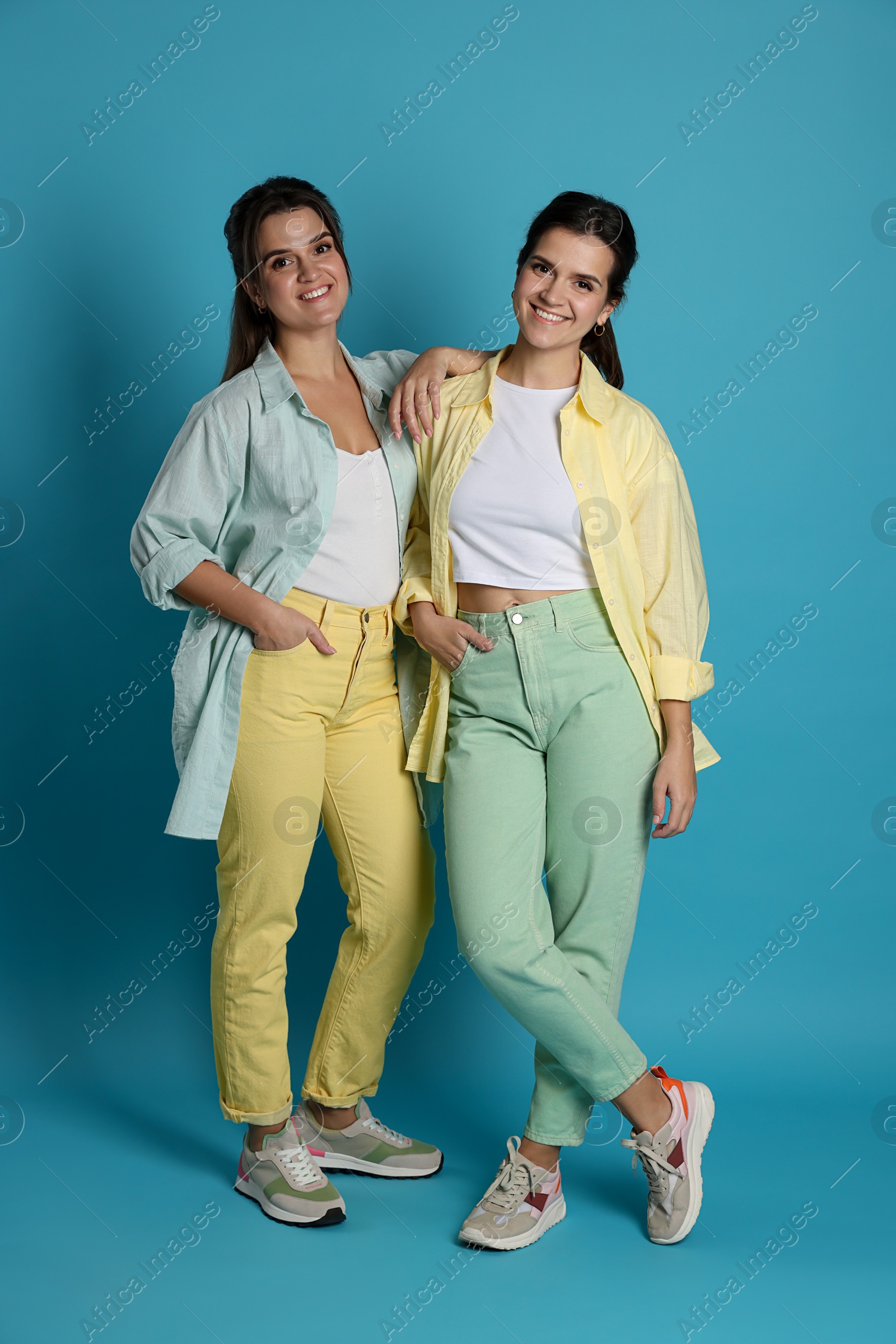 Photo of Portrait of beautiful twin sisters on light blue background