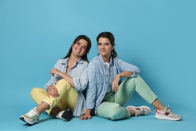 Photo of Portrait of beautiful twin sisters on light blue background