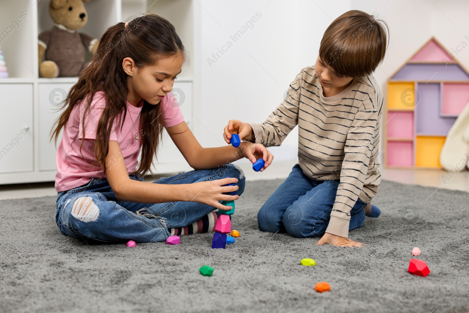 Photo of Children playing with balancing stones on floor indoors