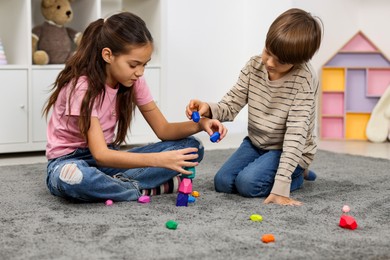 Photo of Children playing with balancing stones on floor indoors