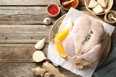 Photo of Uncooked turkey, orange slices and spices on wooden table, flat lay. Space for text