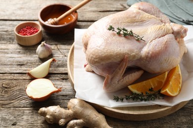 Photo of Uncooked turkey, orange slices and spices on wooden table, closeup