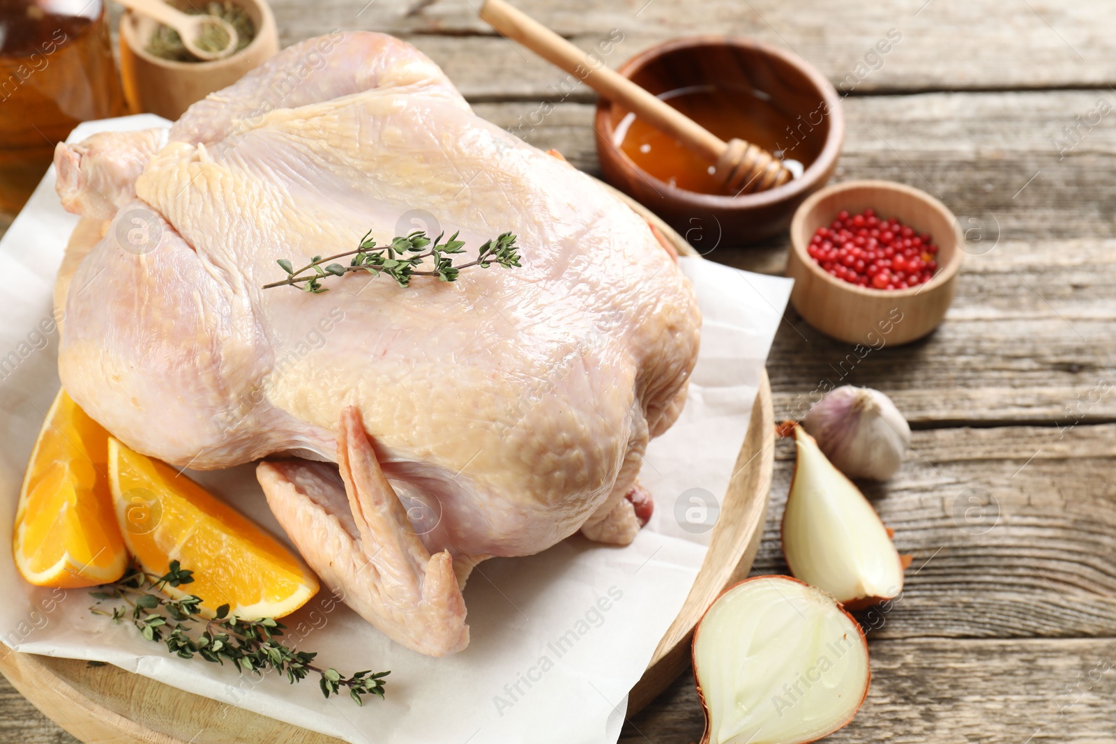 Photo of Uncooked turkey, orange slices and spices on wooden table, closeup