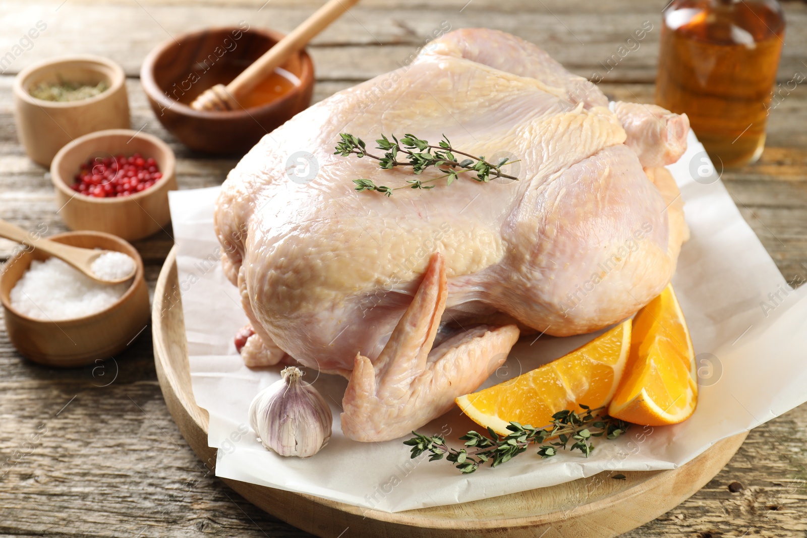 Photo of Uncooked turkey, orange slices and spices on wooden table, closeup