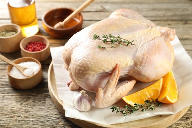 Photo of Uncooked turkey, orange slices and spices on wooden table, closeup