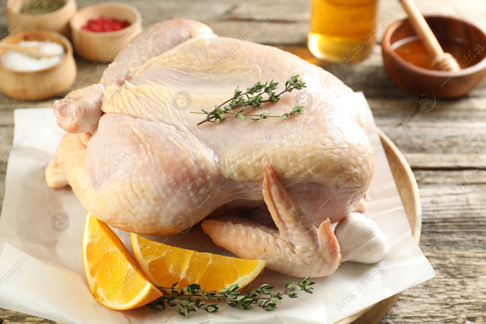 Photo of Uncooked turkey, orange slices and spices on wooden table, closeup