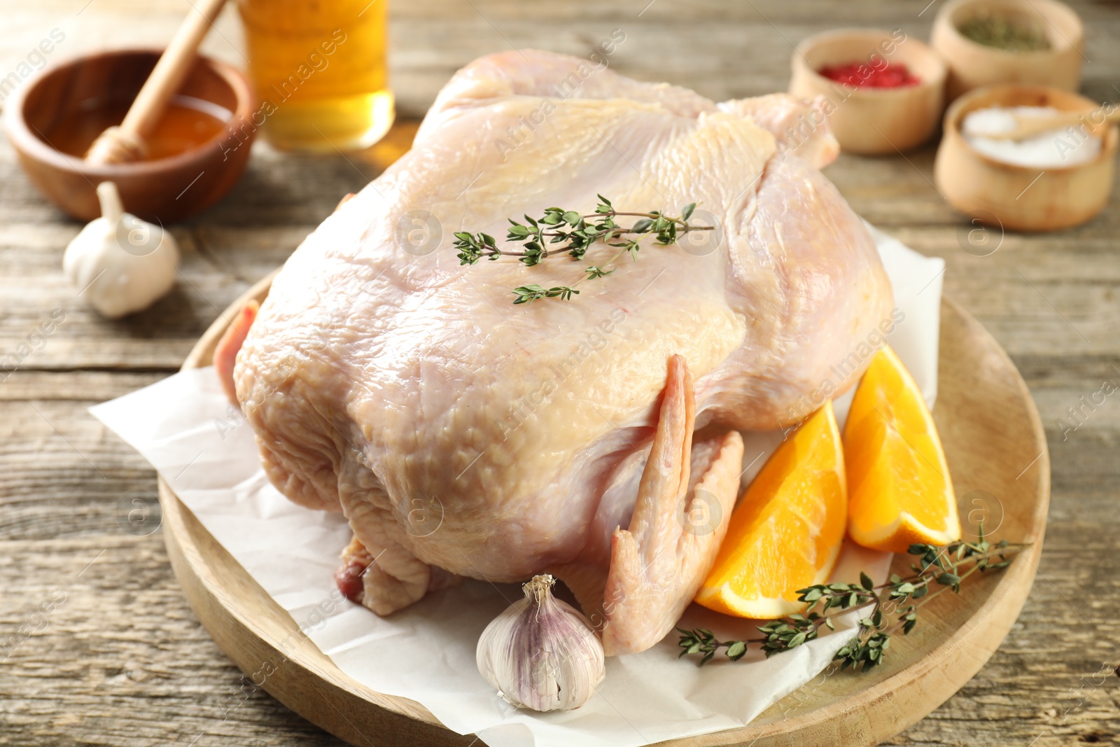 Photo of Uncooked turkey, orange slices and spices on wooden table, closeup