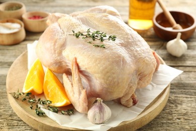 Photo of Uncooked turkey, orange slices and spices on wooden table, closeup