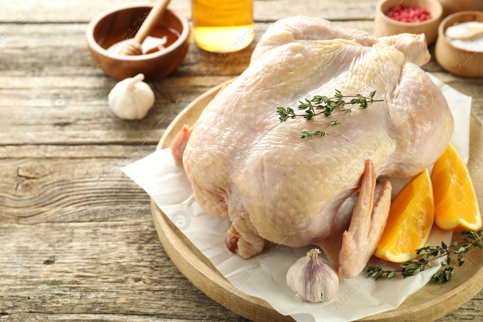 Photo of Uncooked turkey, orange slices and spices on wooden table, closeup