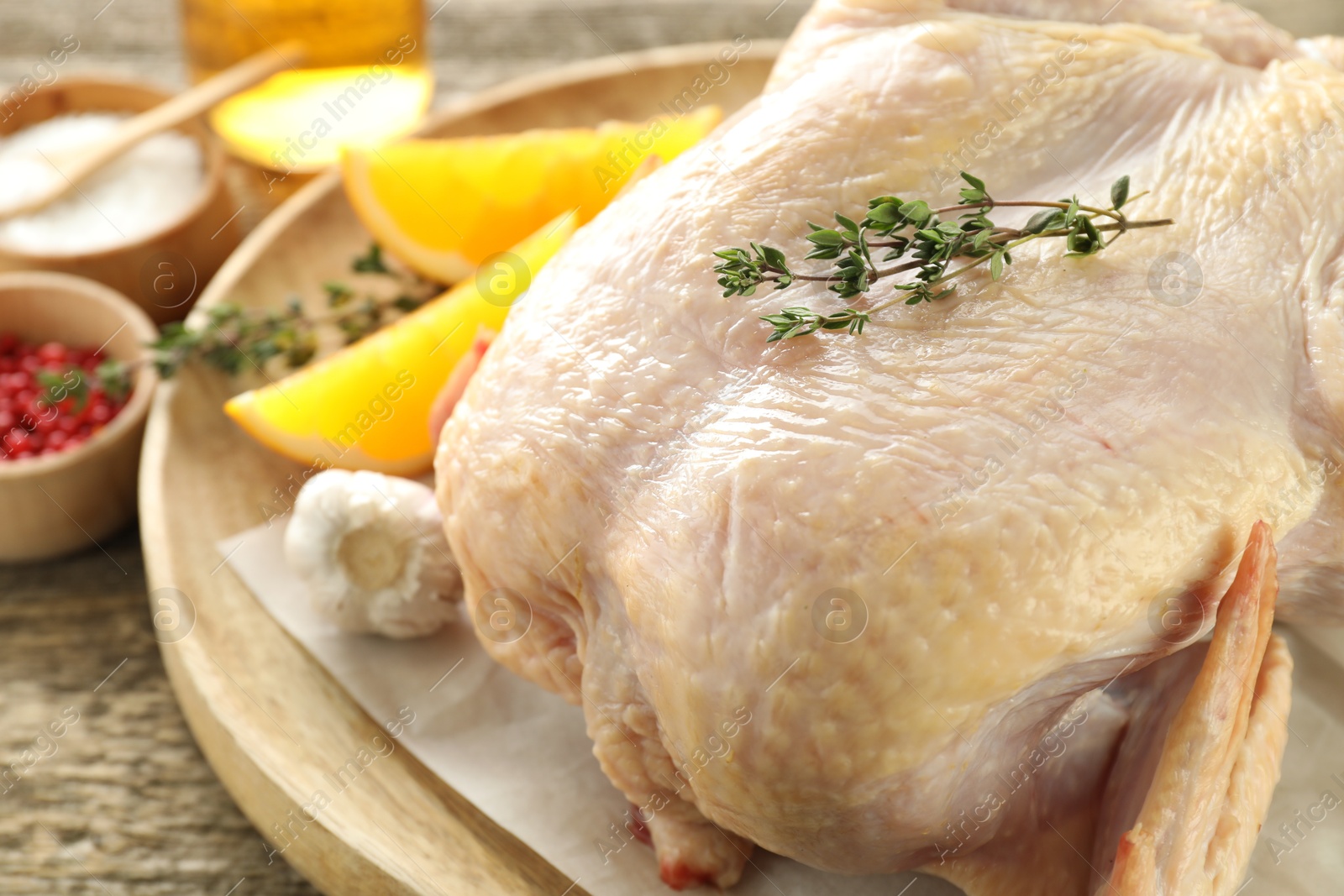 Photo of Uncooked turkey, orange slices and spices on wooden table, closeup