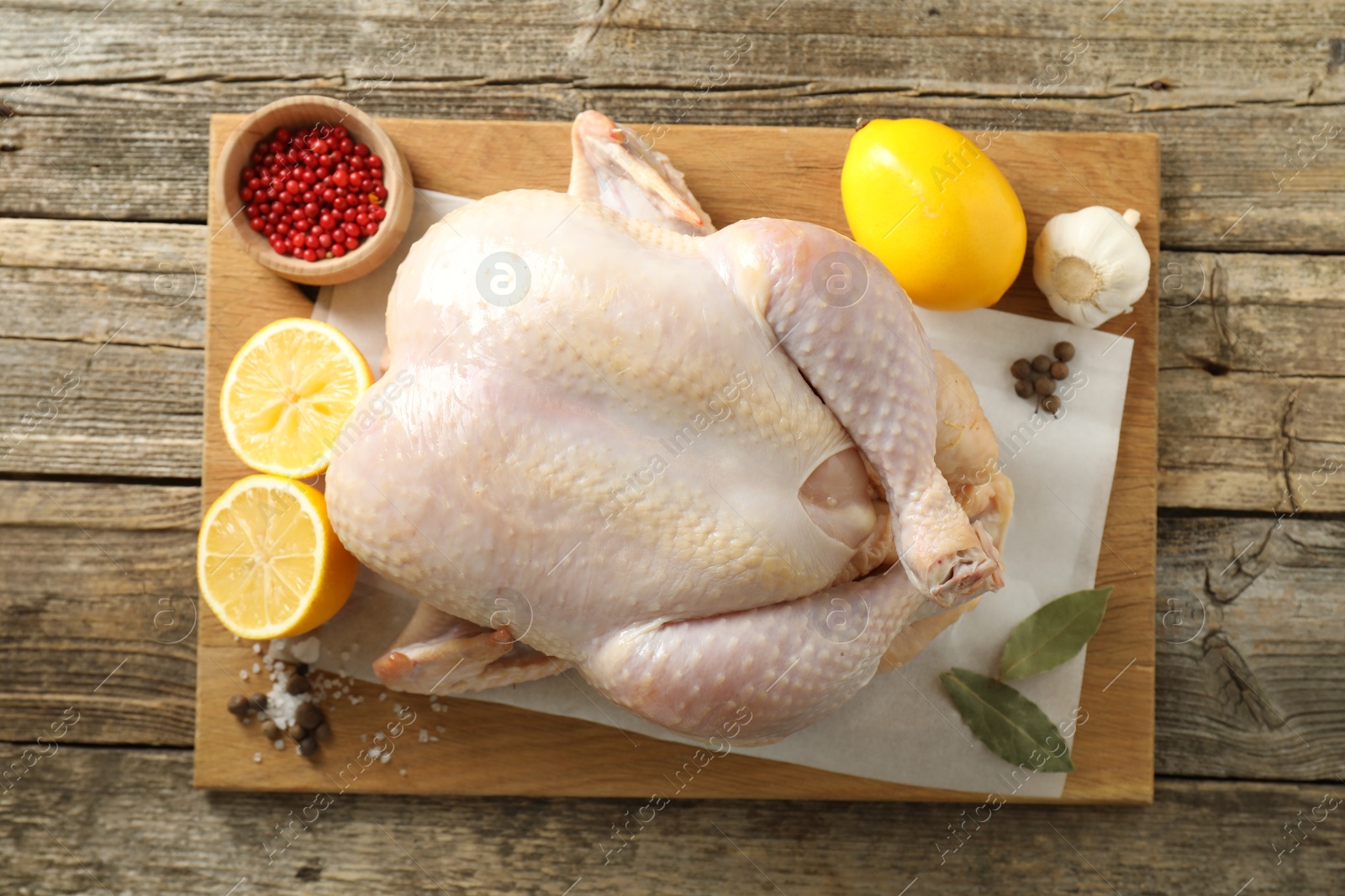 Photo of Uncooked turkey, lemon and spices on wooden table, top view