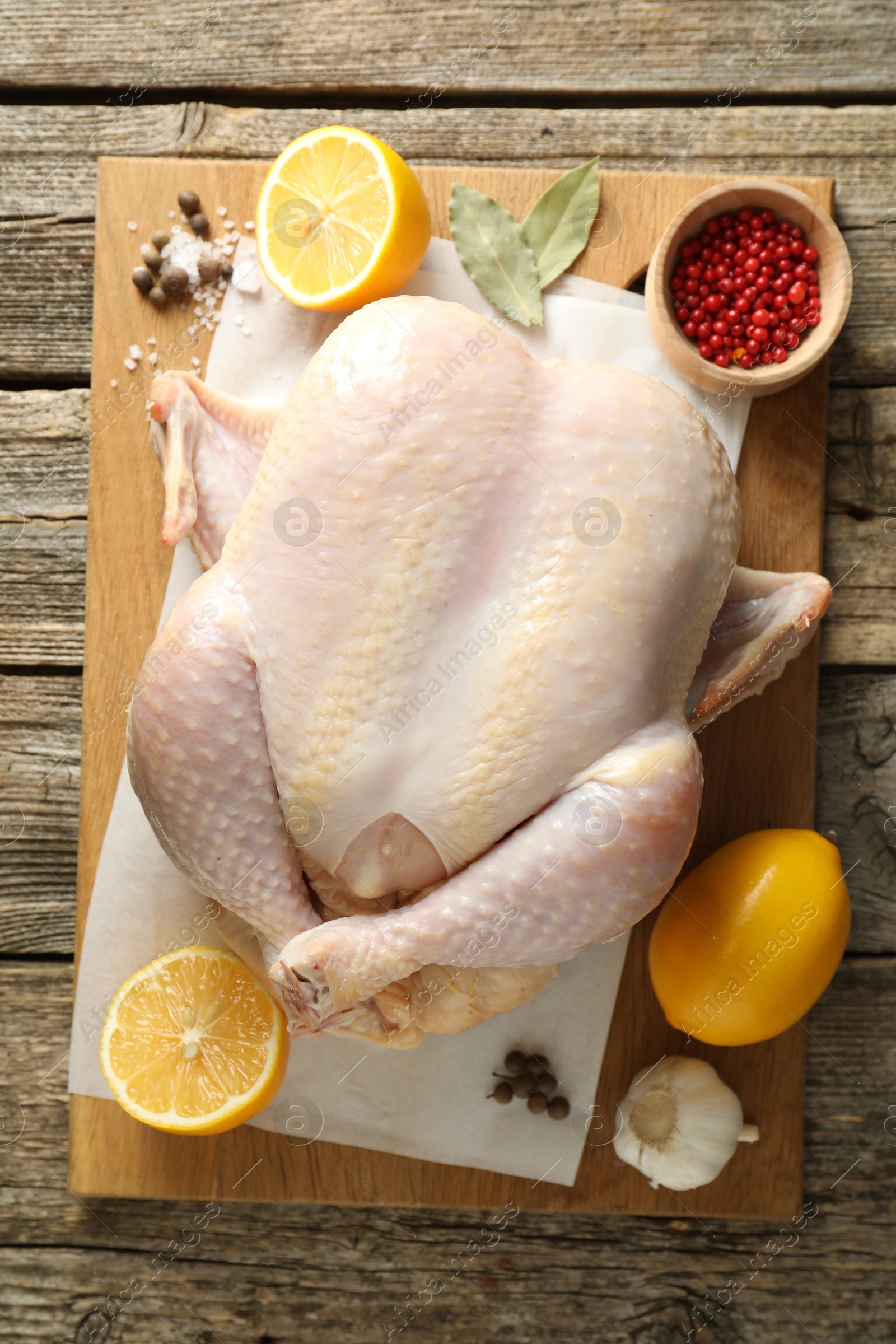 Photo of Uncooked turkey, lemon and spices on wooden table, top view