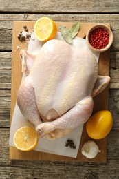 Photo of Uncooked turkey, lemon and spices on wooden table, top view