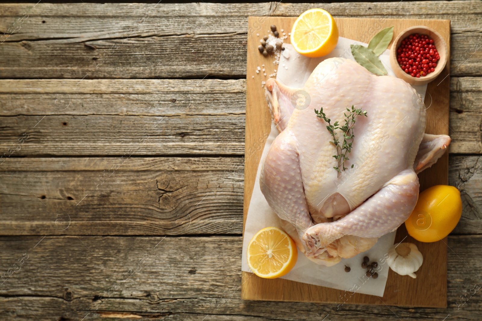 Photo of Uncooked turkey, lemon and spices on wooden table, top view. Space for text