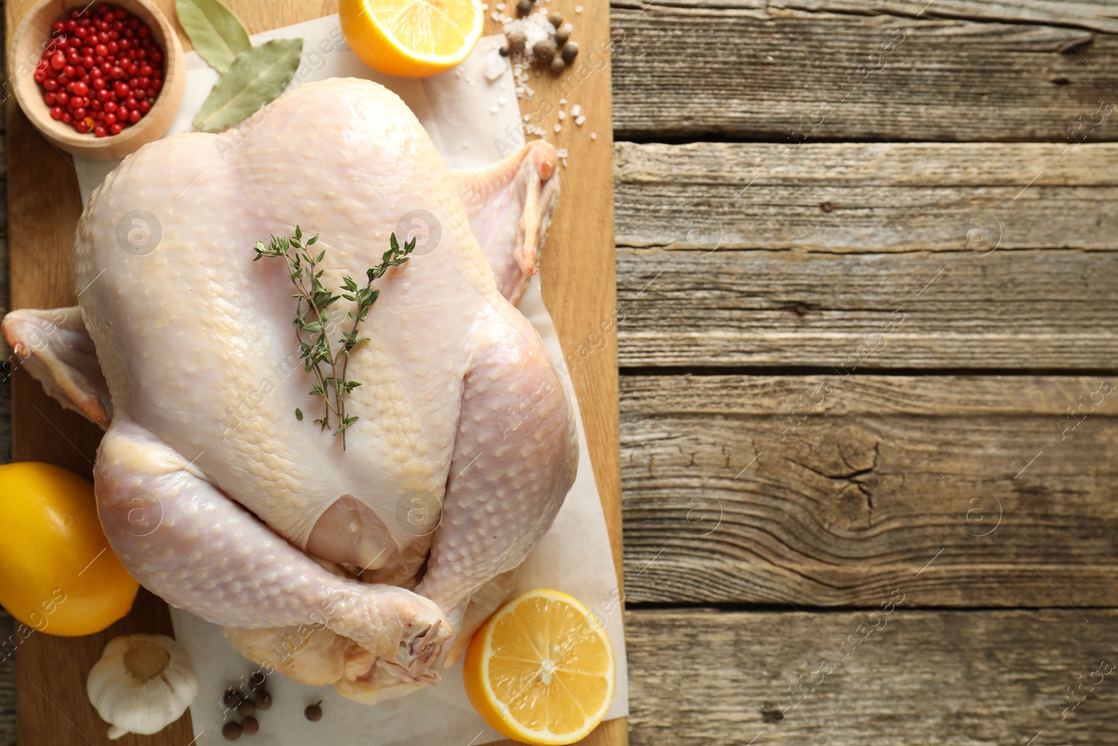 Photo of Uncooked turkey, lemon and spices on wooden table, top view. Space for text