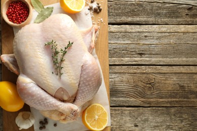 Photo of Uncooked turkey, lemon and spices on wooden table, top view. Space for text