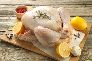 Photo of Uncooked turkey, lemon and spices on wooden table, closeup