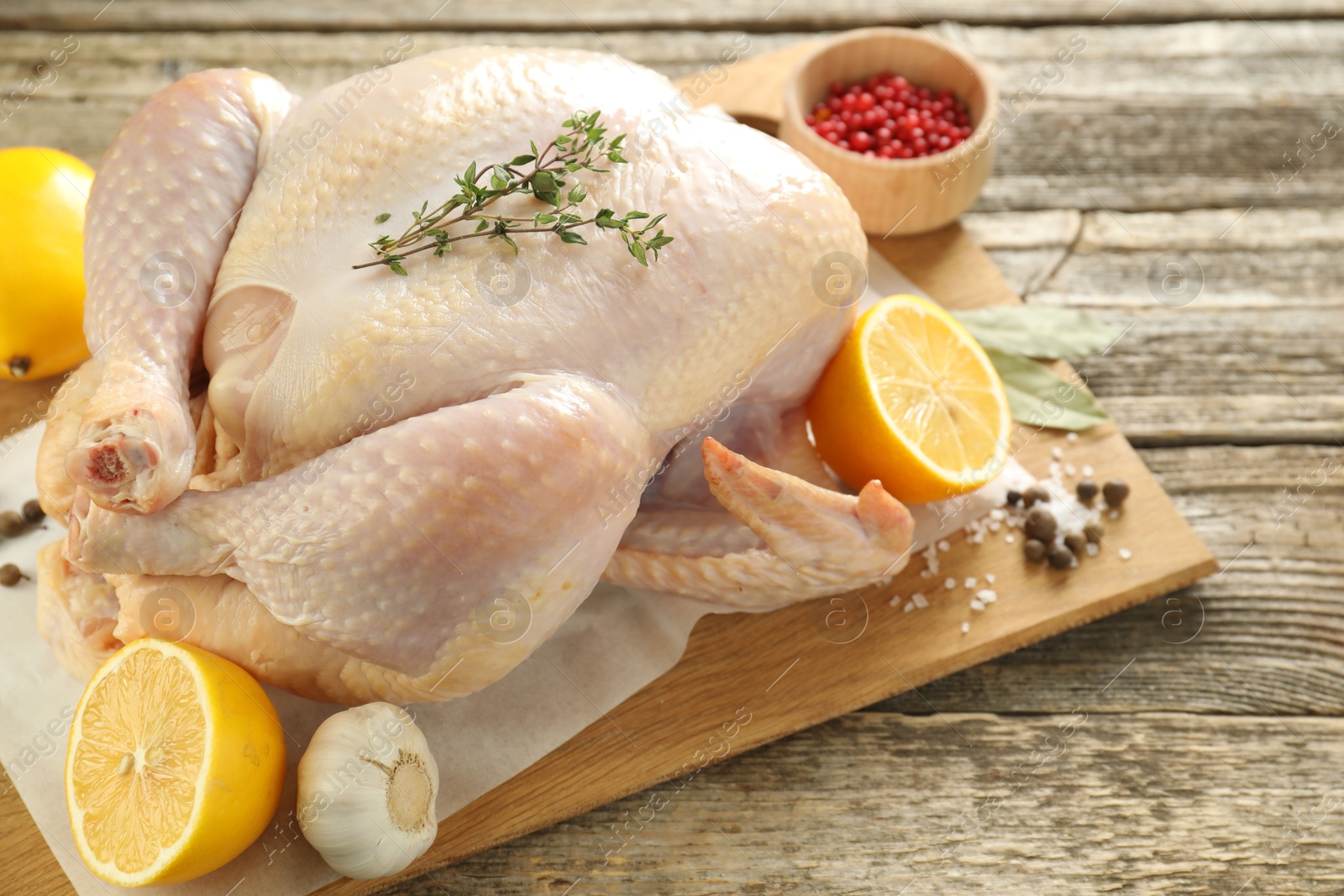 Photo of Uncooked turkey, lemon and spices on wooden table, closeup