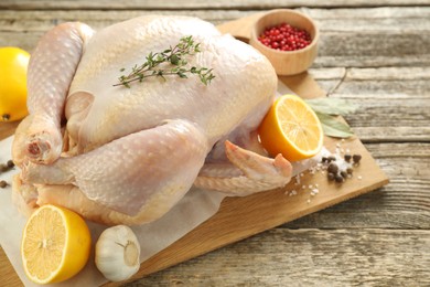 Photo of Uncooked turkey, lemon and spices on wooden table, closeup