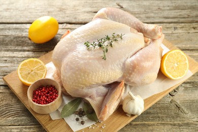 Photo of Uncooked turkey, lemon and spices on wooden table, closeup