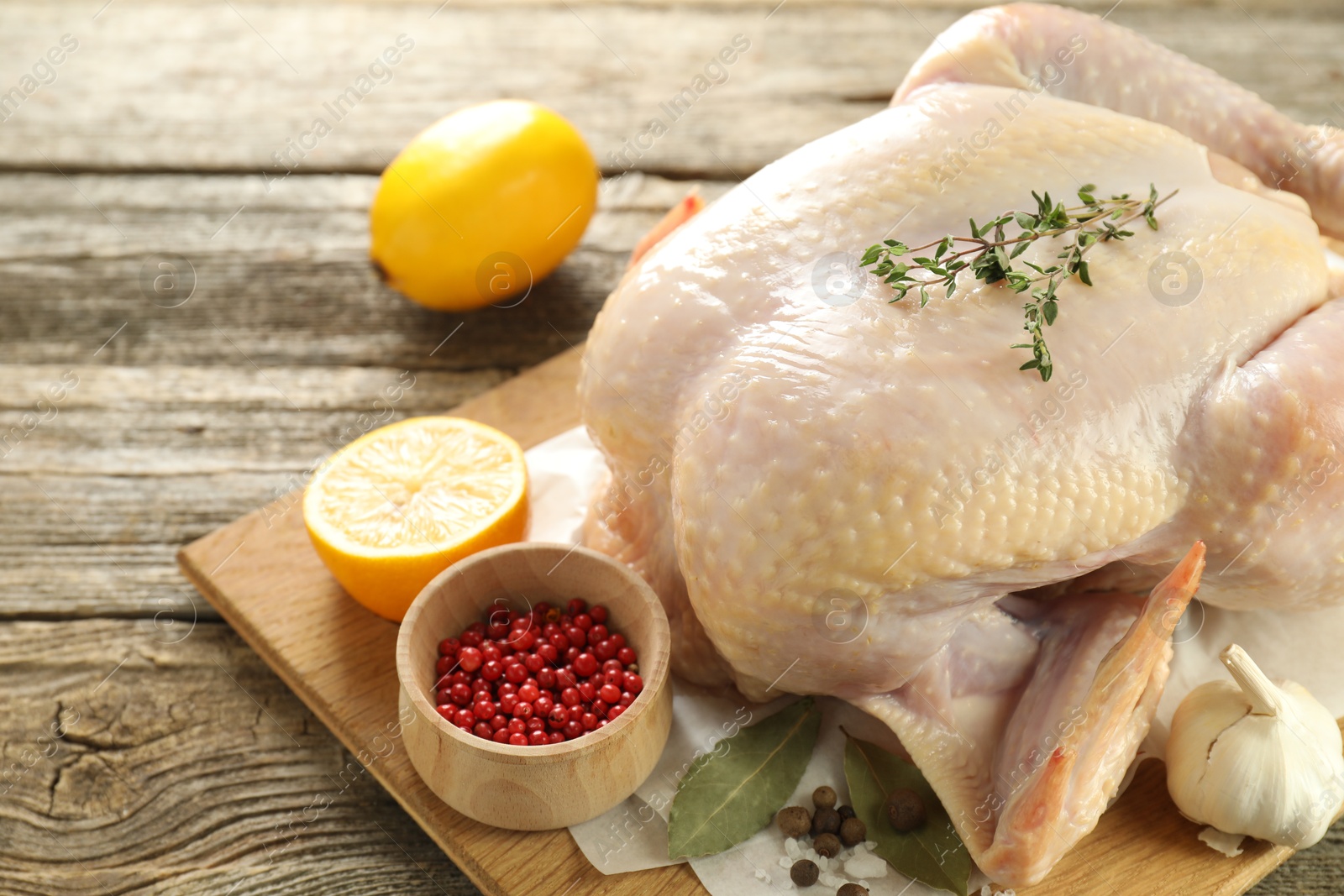 Photo of Uncooked turkey, lemon and spices on wooden table, closeup