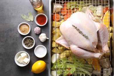 Photo of Raw turkey with different vegetables and spices on grey table, flat lay