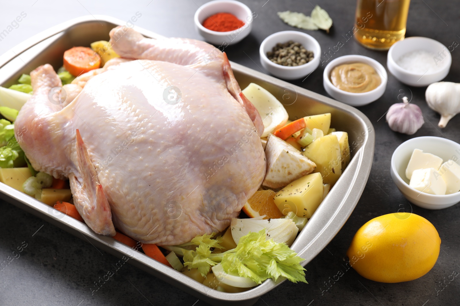 Photo of Raw turkey with different vegetables and spices on grey table, closeup