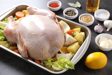 Photo of Raw turkey with different vegetables and spices on grey table, closeup