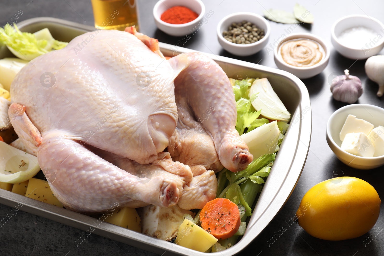 Photo of Raw turkey with different vegetables and spices on grey table, closeup