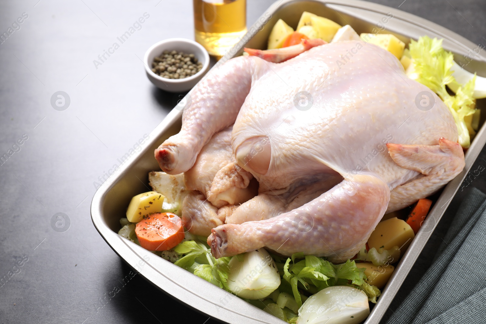 Photo of Raw turkey with different vegetables and spices on grey table, closeup