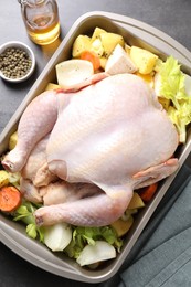 Photo of Raw turkey with different vegetables and spices on grey table, above view