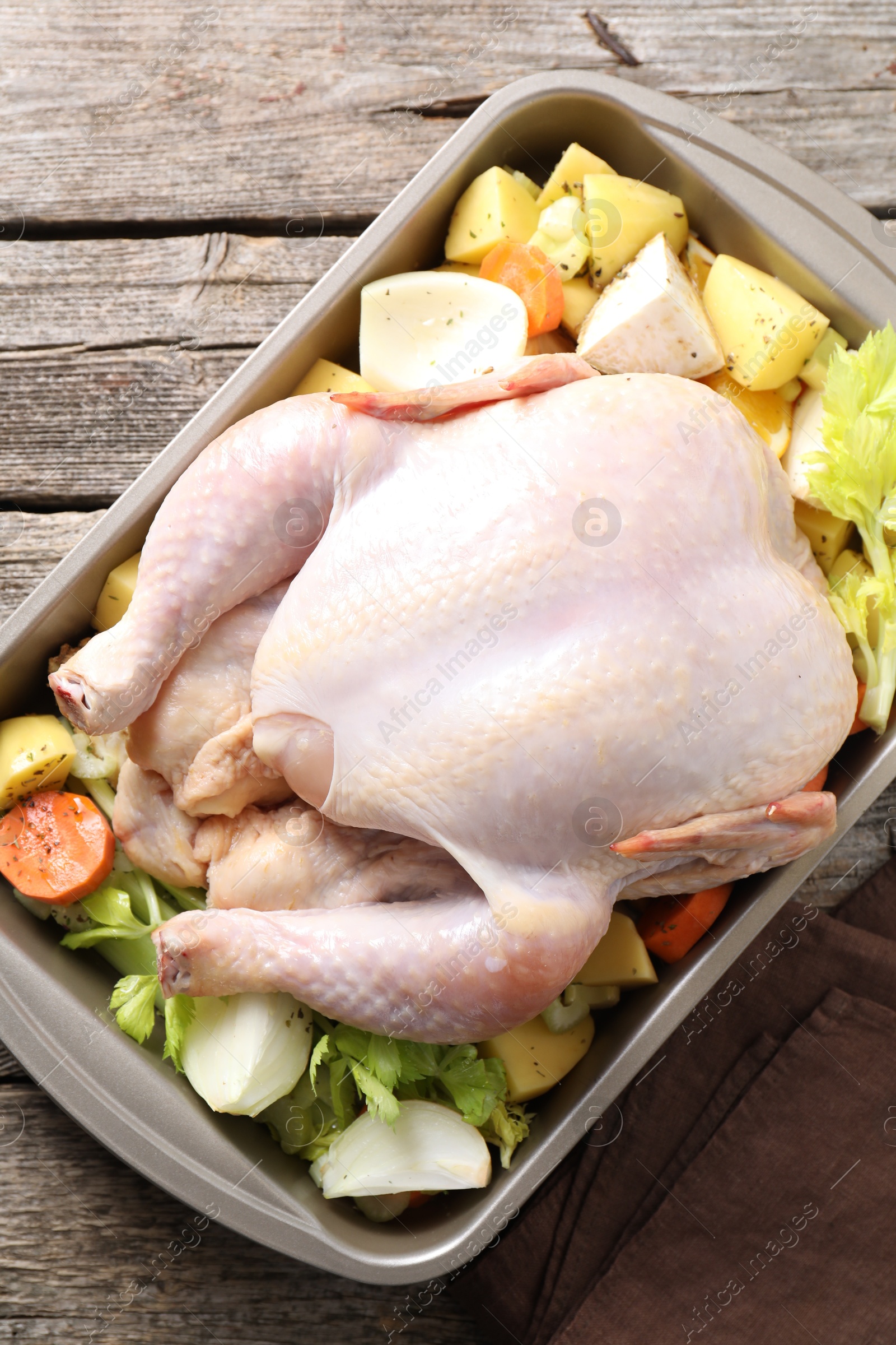 Photo of Raw turkey and vegetables in baking dish on wooden table, top view