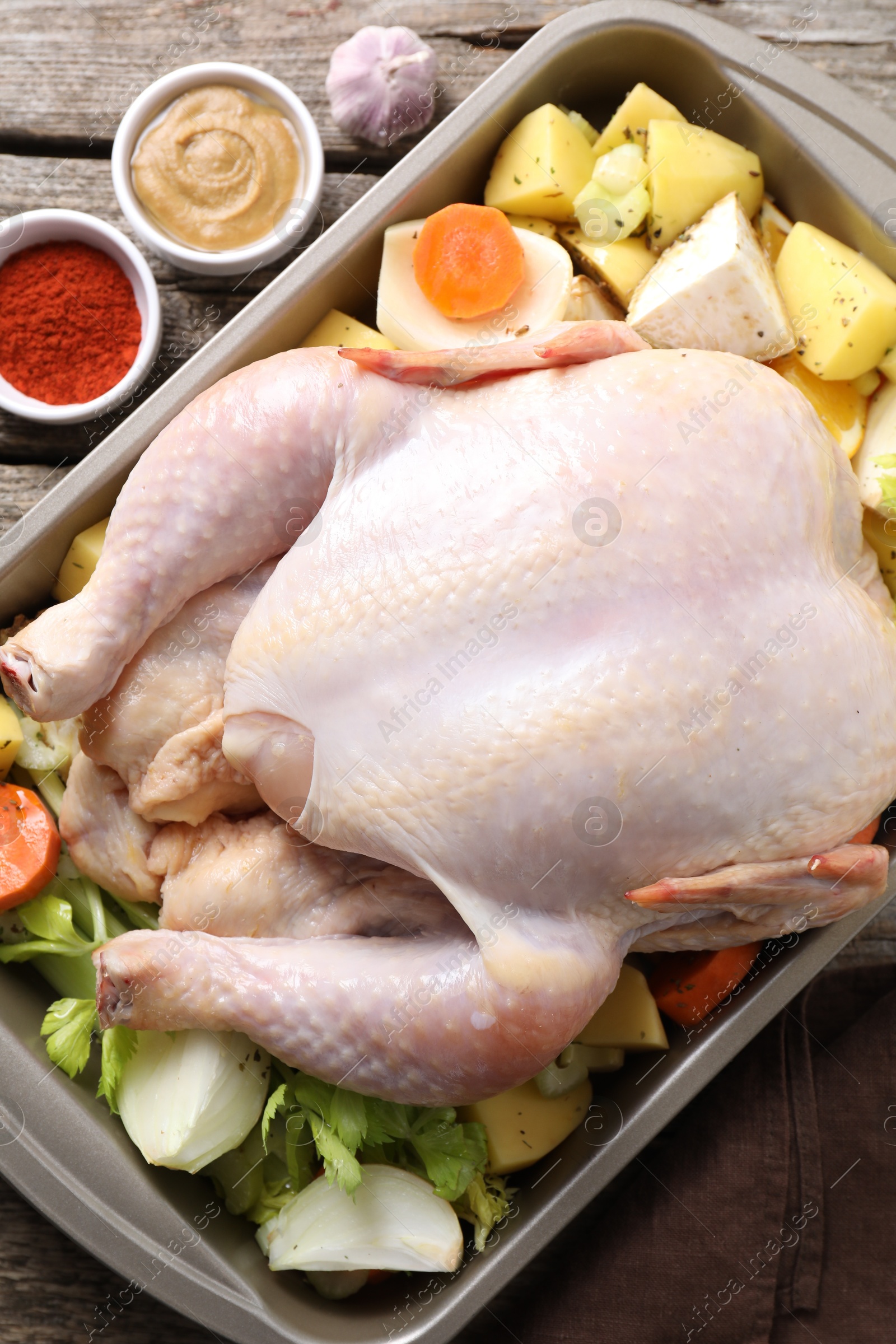 Photo of Raw turkey with different vegetables and spices on wooden table, top view