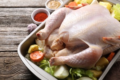 Photo of Raw turkey with different vegetables and spices on wooden table, closeup