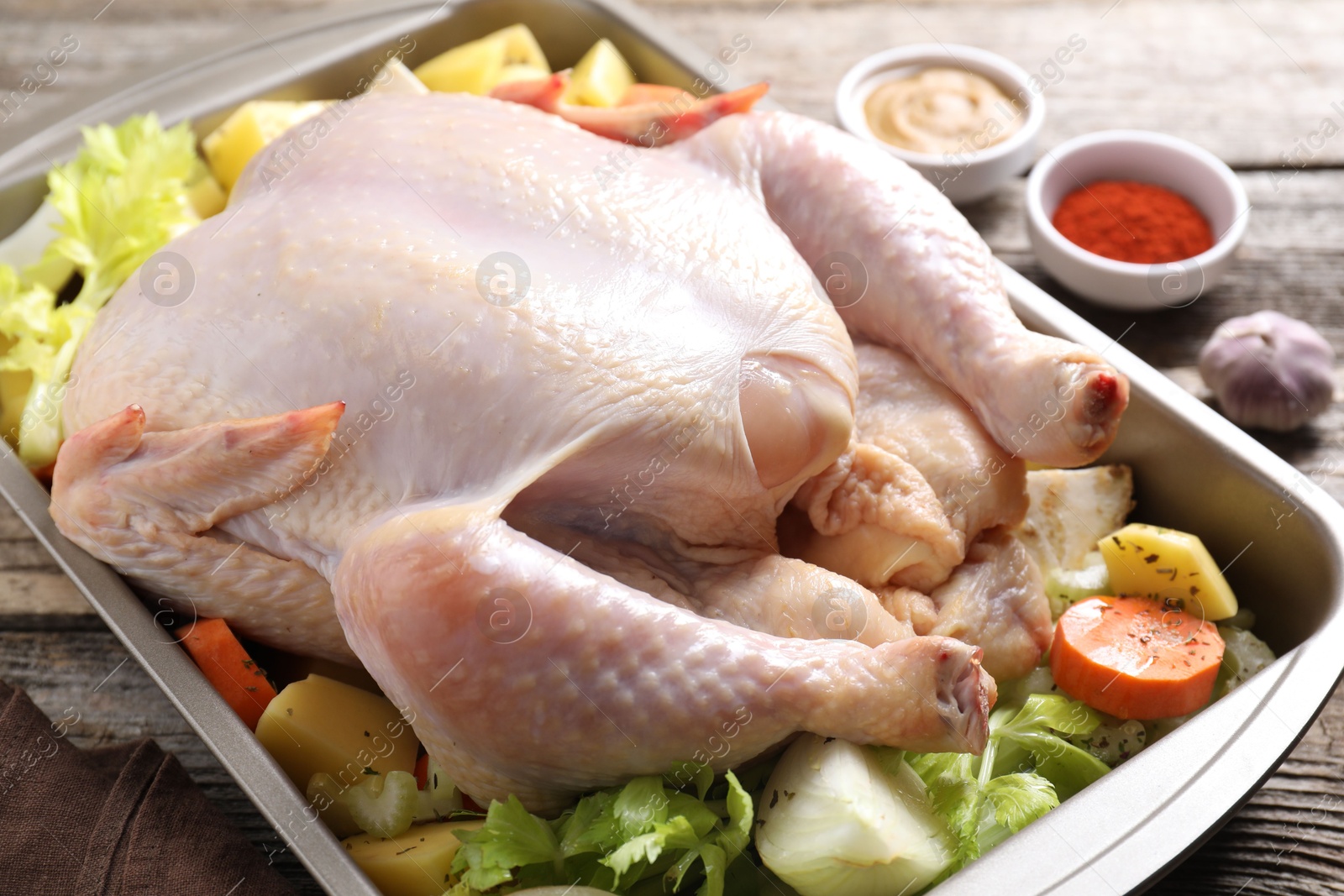 Photo of Raw turkey with different vegetables and spices on wooden table, closeup