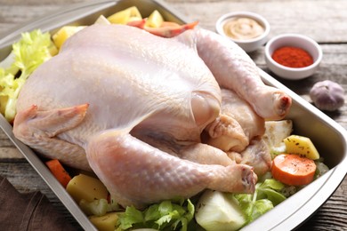 Photo of Raw turkey with different vegetables and spices on wooden table, closeup