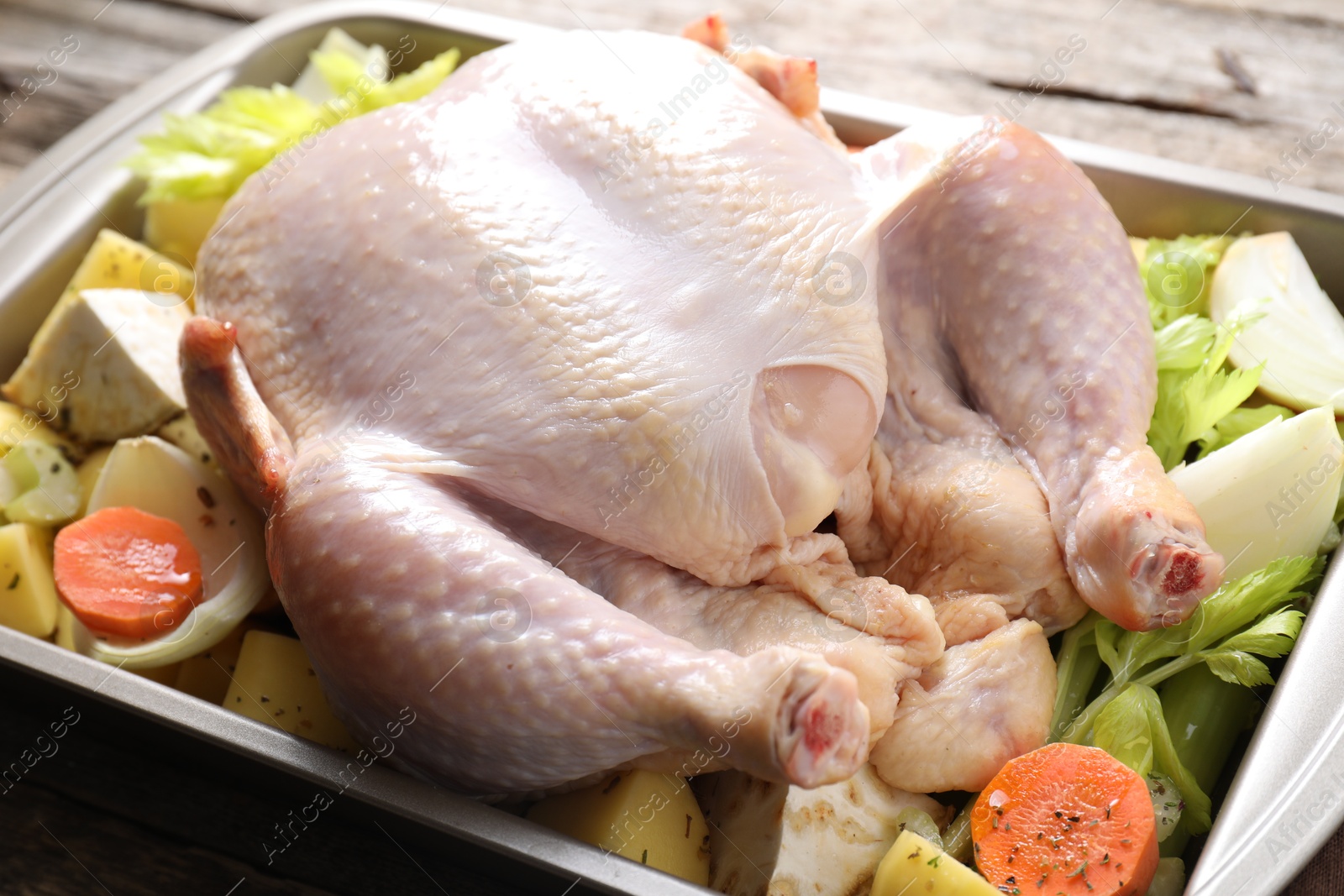 Photo of Raw turkey and vegetables in baking dish on wooden table, closeup