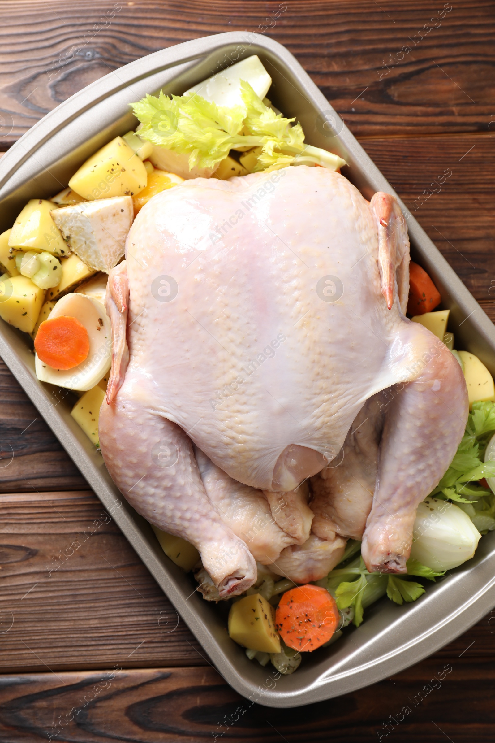 Photo of Raw turkey and vegetables in baking dish on wooden table, top view