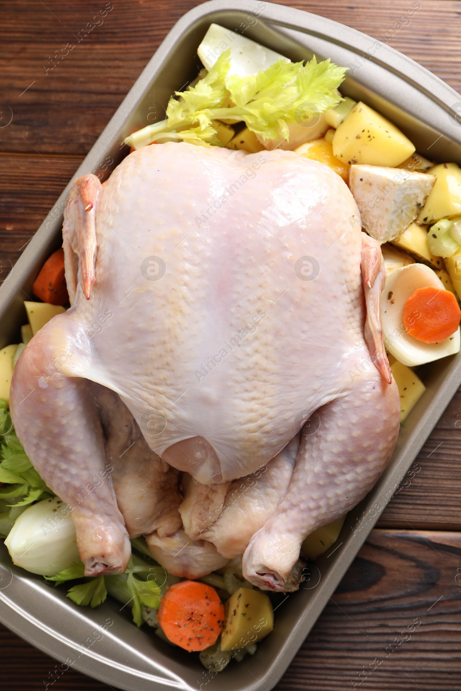 Photo of Raw turkey and vegetables in baking dish on wooden table, top view