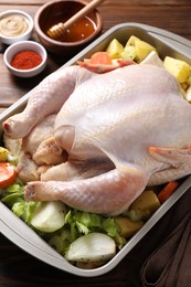 Raw turkey with different vegetables and spices on wooden table, closeup