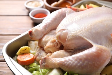 Photo of Raw turkey with different vegetables and spices on wooden table, closeup