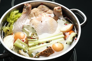 Photo of Whole raw turkey, cut onion, celery and spices in pot, closeup