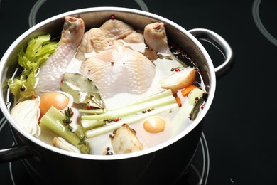 Photo of Whole fresh turkey, cut onion, celery and spices in pot on stove, closeup