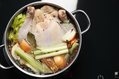 Photo of Whole fresh turkey, cut onion, celery and spices in pot on stove, top view