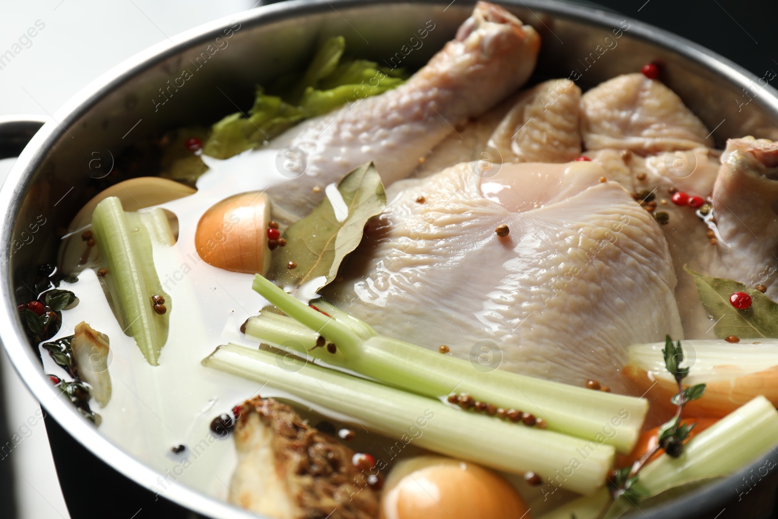 Photo of Whole raw turkey, cut onion, celery and spices in pot, closeup