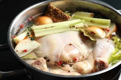 Photo of Whole raw turkey, cut onion, celery and spices in pot, closeup